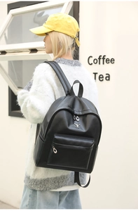 Close-up of black synthetic leather backpack featuring a silver cartoon monster emblem