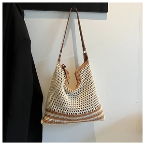 Detail of hollow crochet straw tote bag with brown leather strap and contrast bottom