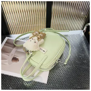 Close-up of light green lychee texture PU leather handbag with cute plush bear charm
