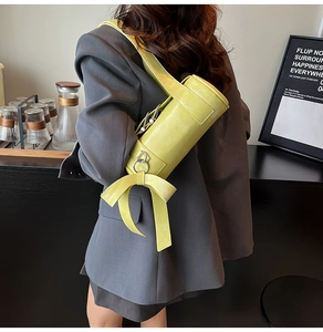 Detail of lime yellow Boston bag with large decorative bow and wide shoulder strap