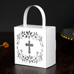 Detail of laser-cut cross and floral pattern on white gift box with handles