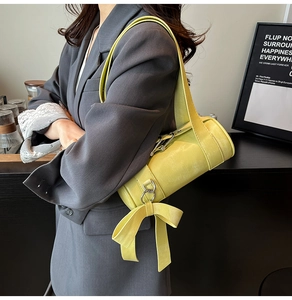 Gros plan du sac Boston jaune citron avec détail nœud papillon et anneaux argentés