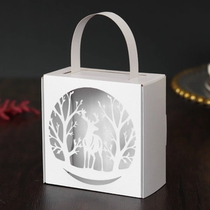 Detail of white laser-cut Christmas candy box featuring an intricate forest deer pattern