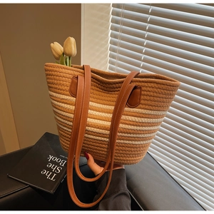 Detail of woven straw tote bag with brown leather straps and summer striped pattern