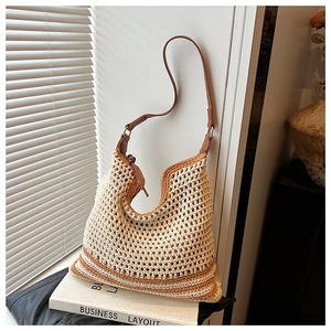 Close-up of beige straw tote bag with brown leather straps and striped knit detail