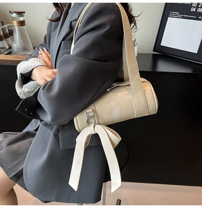 Détail d'un sac cylindre beige avec un grand nœud décoratif et une texture en cuir PU premium