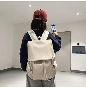 Detail of a creamy white PU leather backpack shown on back with drawstring closure and pockets