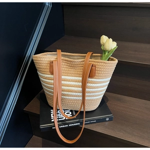Detail of hand-woven rope tote bag with leather handles and white stripe pattern