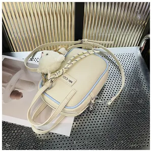 Detail of cream white camera bag with blue trim and cute white plush bear charm