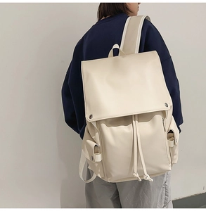 Detail view of cream vintage backpack with flap closure and drawstring on model's back