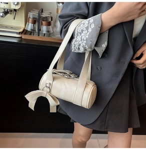 Détail du sac Boston crème cylindrique avec nœud latéral et sangle à boucle métallique