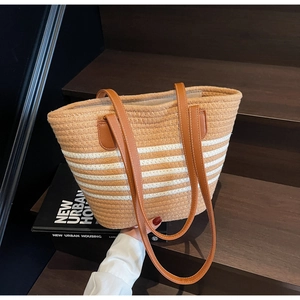 Detail of woven rope tote bag featuring brown leather handles and striped texture