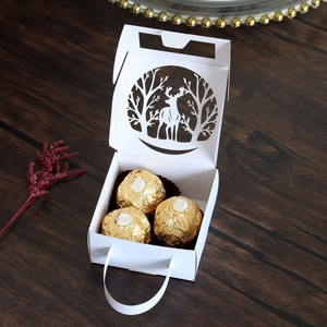 Detail of white laser-cut Christmas candy box with reindeer hollow design and gold chocolates