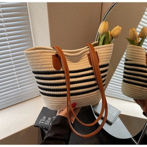 Detail of woven rope tote bag with black stripes and sturdy brown leather handles