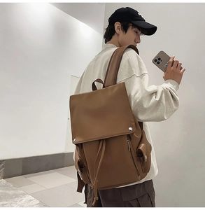 Detail view of the brown leather backpack with drawstring closure and metal buckle hardware
