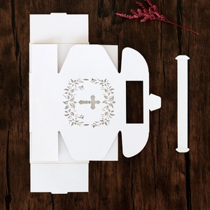 Close-up of laser-cut white cardstock gift box with cross and floral wreath pattern