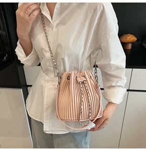 Detail of pink pleated bucket bag with silver chain strap and drawstring closure