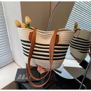 Detail of striped woven tote bag featuring brown leather straps and textured weave
