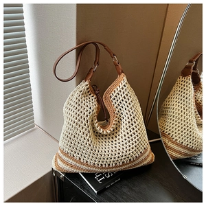 Detail of woven straw tote bag with brown leather straps and striped bottom pattern