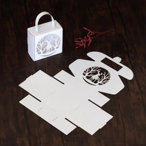 Close-up of white laser-cut Christmas gift box with forest deer patterns and flat card