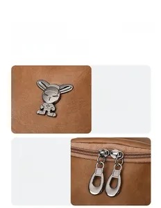 Detail of brown leather backpack featuring a metal rabbit charm and dual metal zippers
