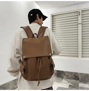 Rear view of model wearing a vintage brown leather backpack with drawstring closure