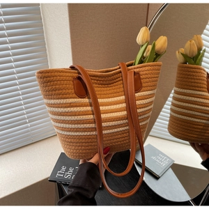 Detail of striped woven tote bag with premium brown leather handles and rope texture