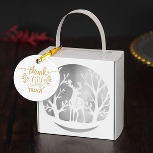 Detail of white laser-cut Christmas candy box with reindeer patterns and thank you tag
