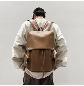 Rear view of model wearing a vintage brown leather backpack with drawstring closure