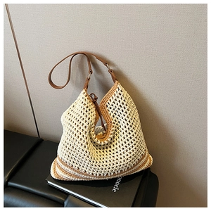 Detail of woven straw hobo bag with brown leather strap and beige patchwork texture