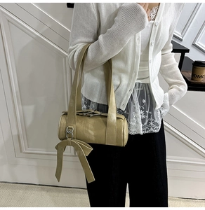 Détail du sac polochon kaki clair avec anneaux métalliques et nœuds en ruban élégants