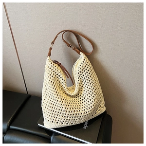 Detail of hollow mesh woven tote with brown leather strap and metal buckle