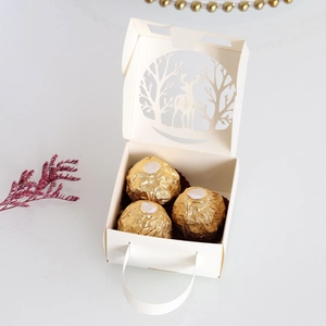 Close-up of white laser-cut Christmas candy box with reindeer and tree hollow design