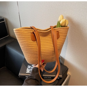 Detail of hand-woven rope tote bag with premium brown leather handles and white stitching