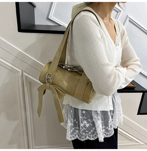 Détail du sac Boston beige avec grand nœud décoratif et anneau en métal argenté poli
