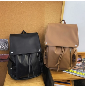 Detail of vintage leather backpacks in black and brown with drawstring and metal buckles