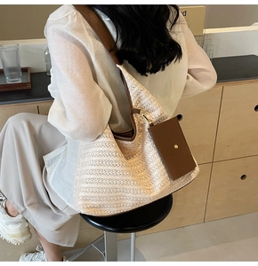 Detailed view of large woven straw tote with brown leather strap and small side pouch
