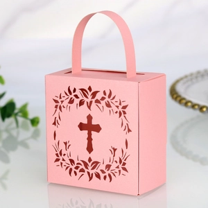Detail of pink laser-cut cross gift box with intricate floral wreath and top handle