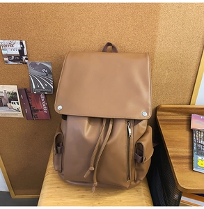 Detailed view of brown vintage leather backpack with drawstring and flap closure on a stool