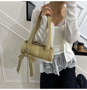 Détail du sac baril kaki avec nœud décoratif et finition en cuir métallisé brillant