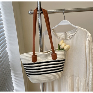 Detail of woven rope tote bag with black stripes and brown leather shoulder straps