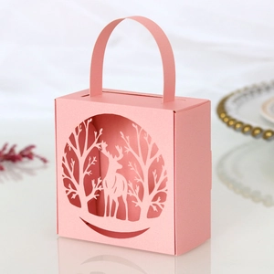 Macro detail of pink paper gift box featuring laser-cut elk and forest silhouette