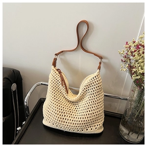Close-up of hollow woven straw bag featuring brown leather strap and zipper closure