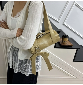 Détail du sac cylindrique vert olive avec grand nœud décoratif et boucles argentées