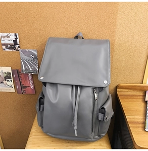 Macro detail of matte grey leather backpack featuring secure drawstring and magnetic flap