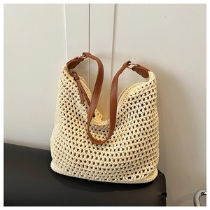Detail of hollow woven cream straw tote bag with brown faux leather shoulder straps