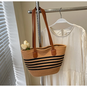 Close-up of rope woven tote bag featuring black stripes and brown leather shoulder straps