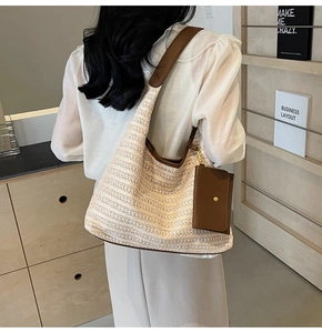 Close-up of woven straw tote bag featuring brown leather trim and a mini coin purse charm