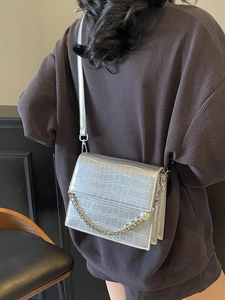Silver crocodile pattern crossbody bag with pearl chain detail shown on a model