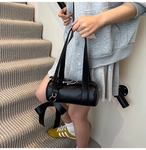 Détail du sac Boston noir avec une grande breloque nœud en cuir et des boucles en argent